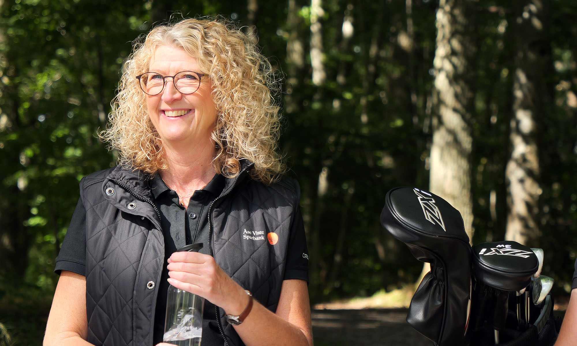 En kvinna med golfbag och vatten