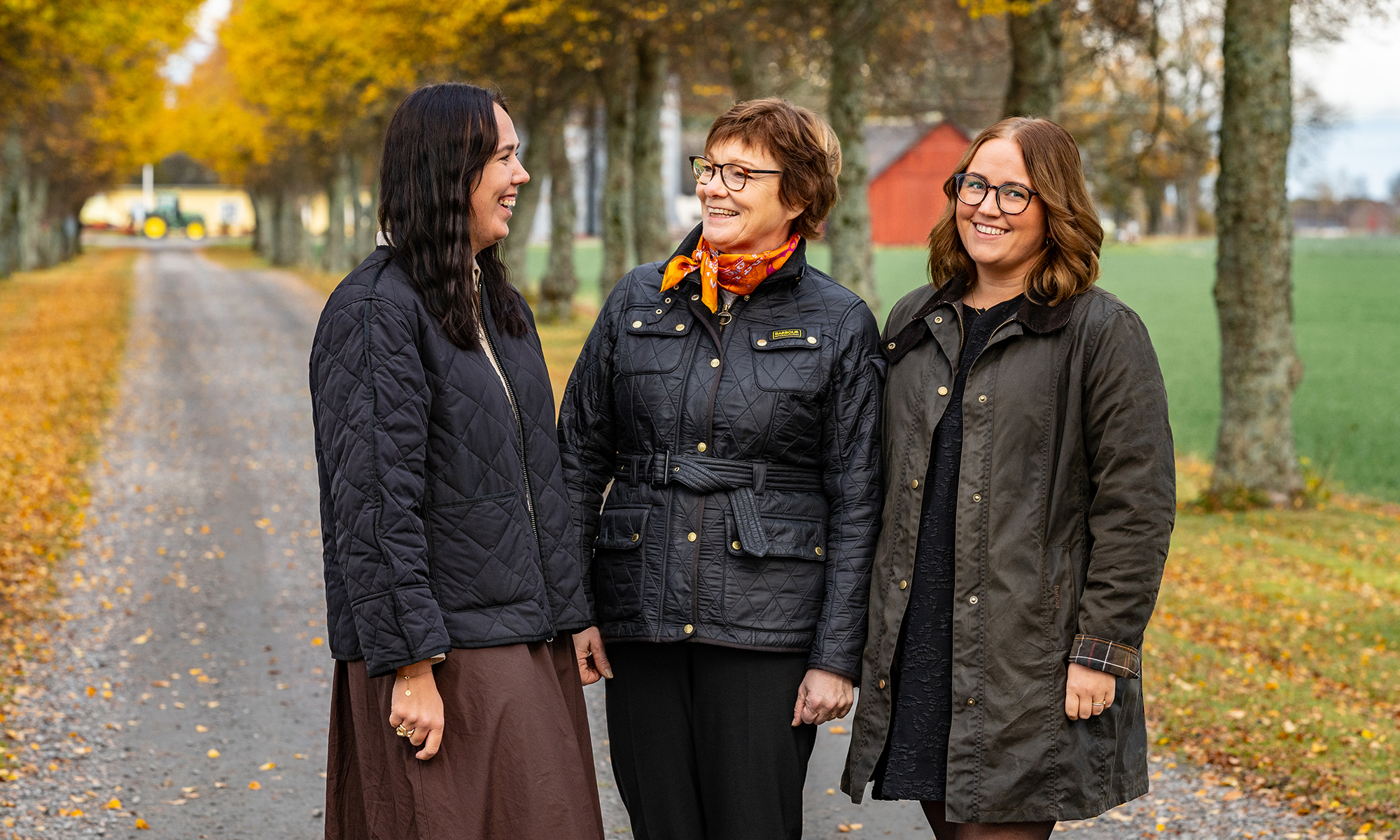 Tre kvinnor står i en alle med höstlöv