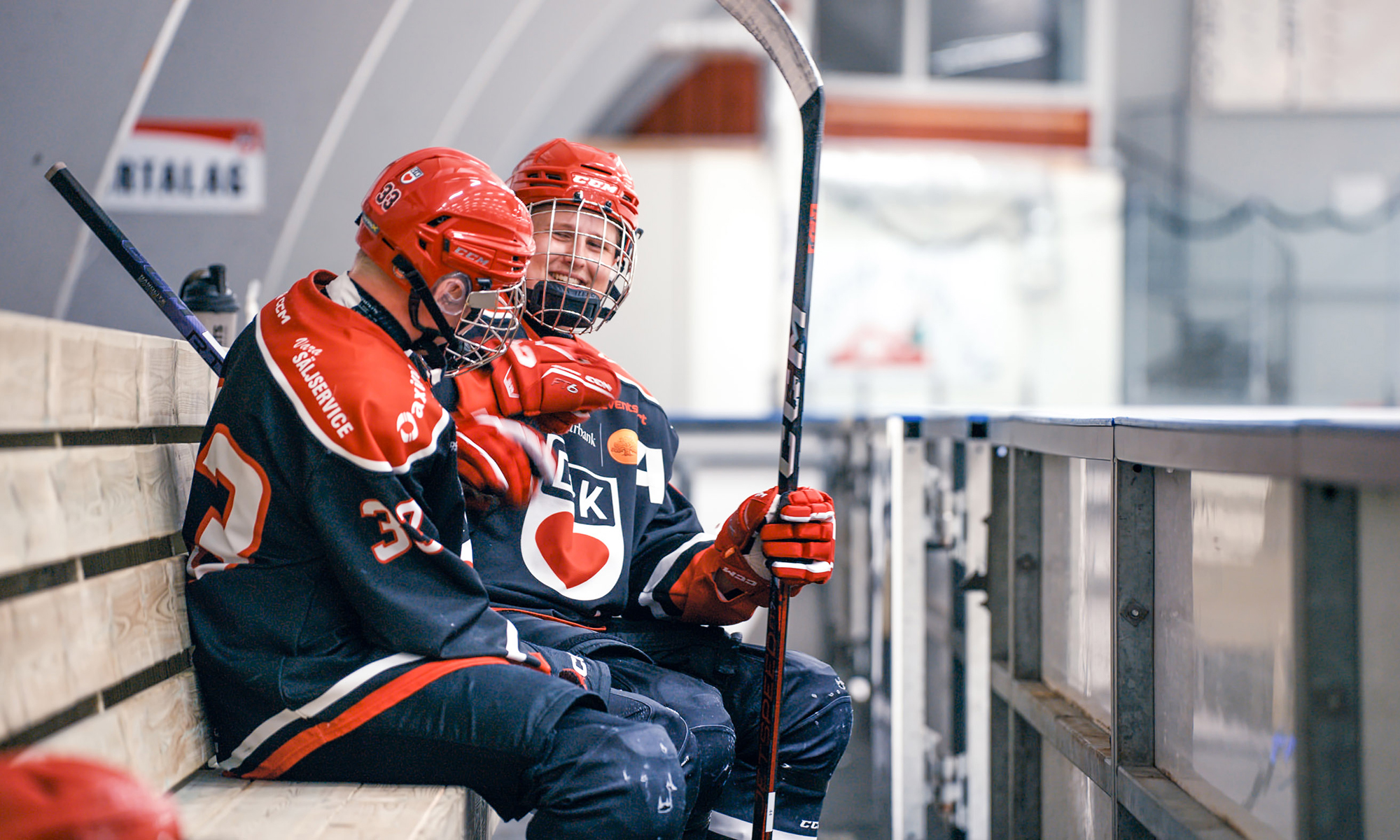 Två hockeykillar sitter i hockeybåset