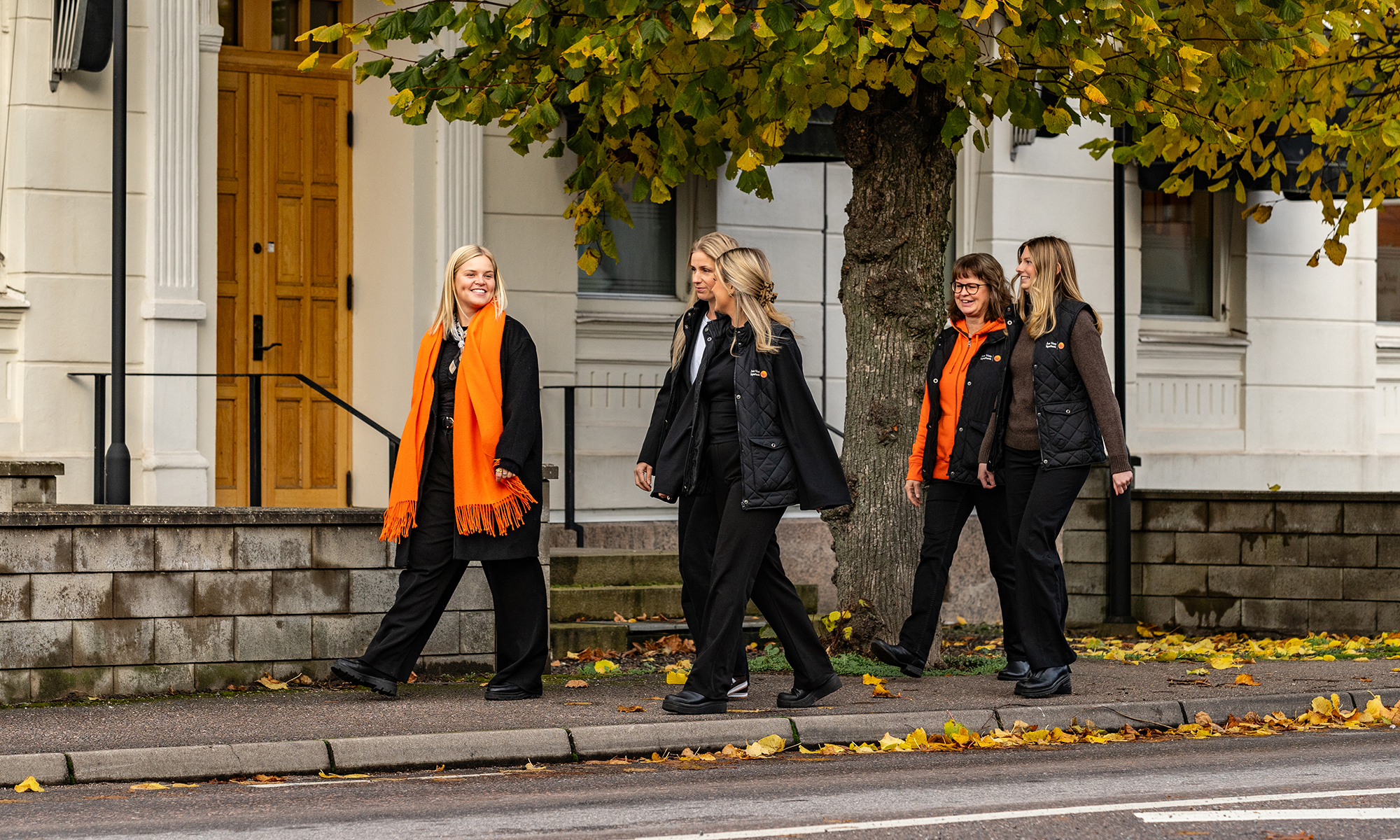 Flera kvinnor går ihop utomhus med höstlöv