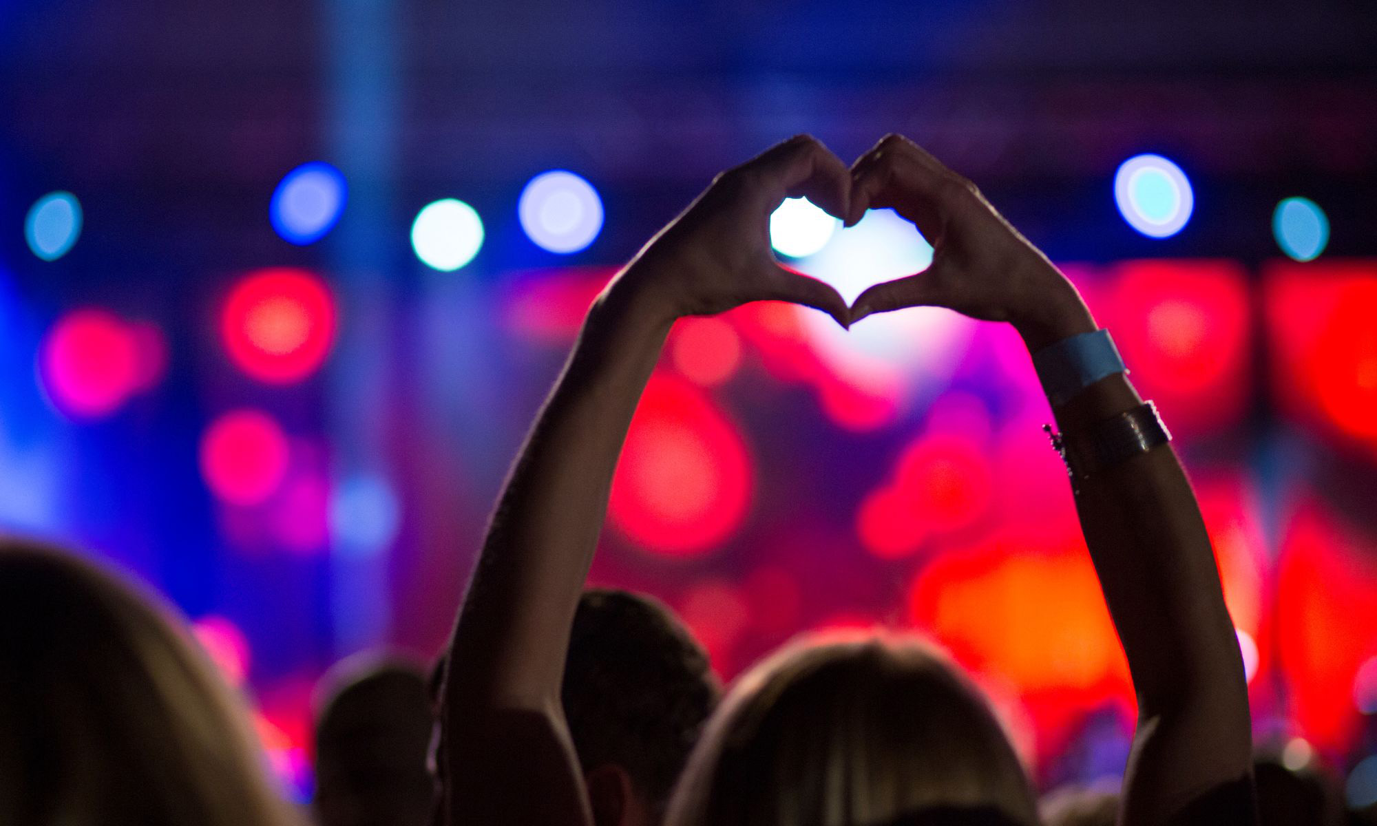 Publik där en kvinna håller upp händerna och formar ett hjärta